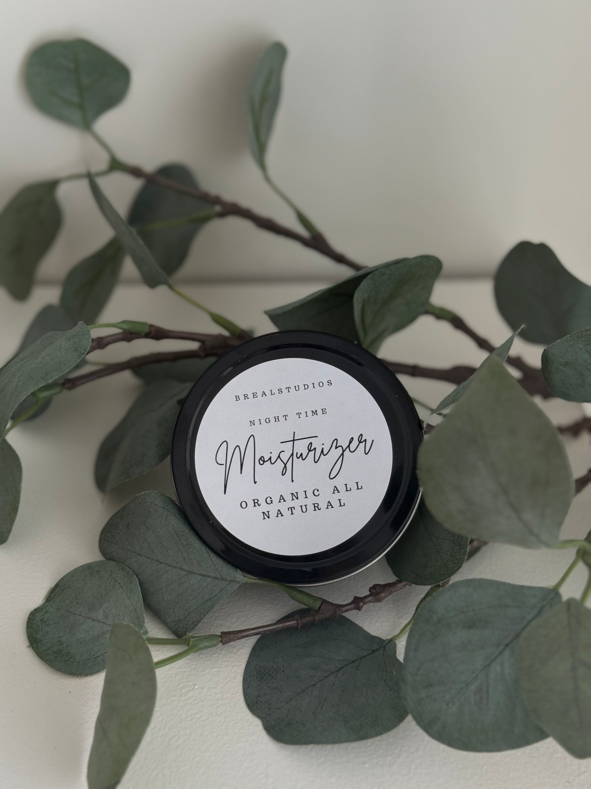 Jar of moisturizer with a plant on a white background