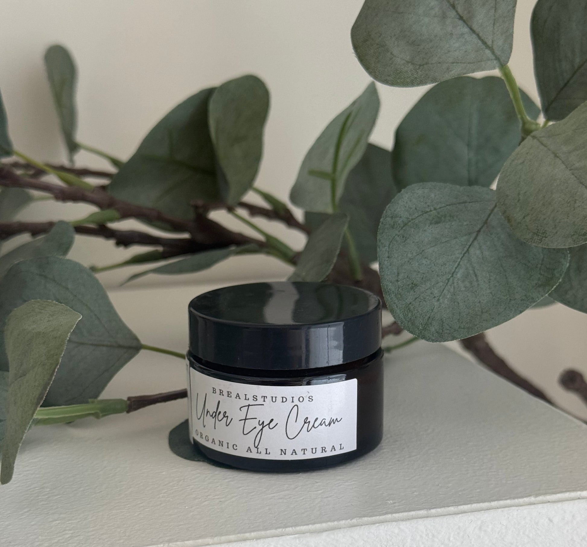 Jar of eye cream with a plant in the foreground